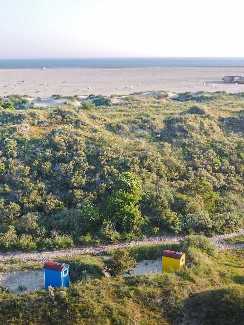 Blick auf einen Strand mit kleinen bunten Häuschen in den Dünen